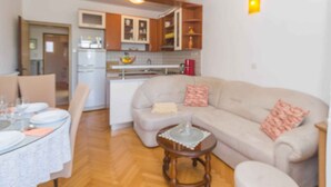 A living room with a beige sofa, a small round table, and a dining area with a table set for four.