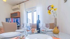 A dining table set with plates, glasses, and cutlery, a bottle of wine, and a vase with flowers.