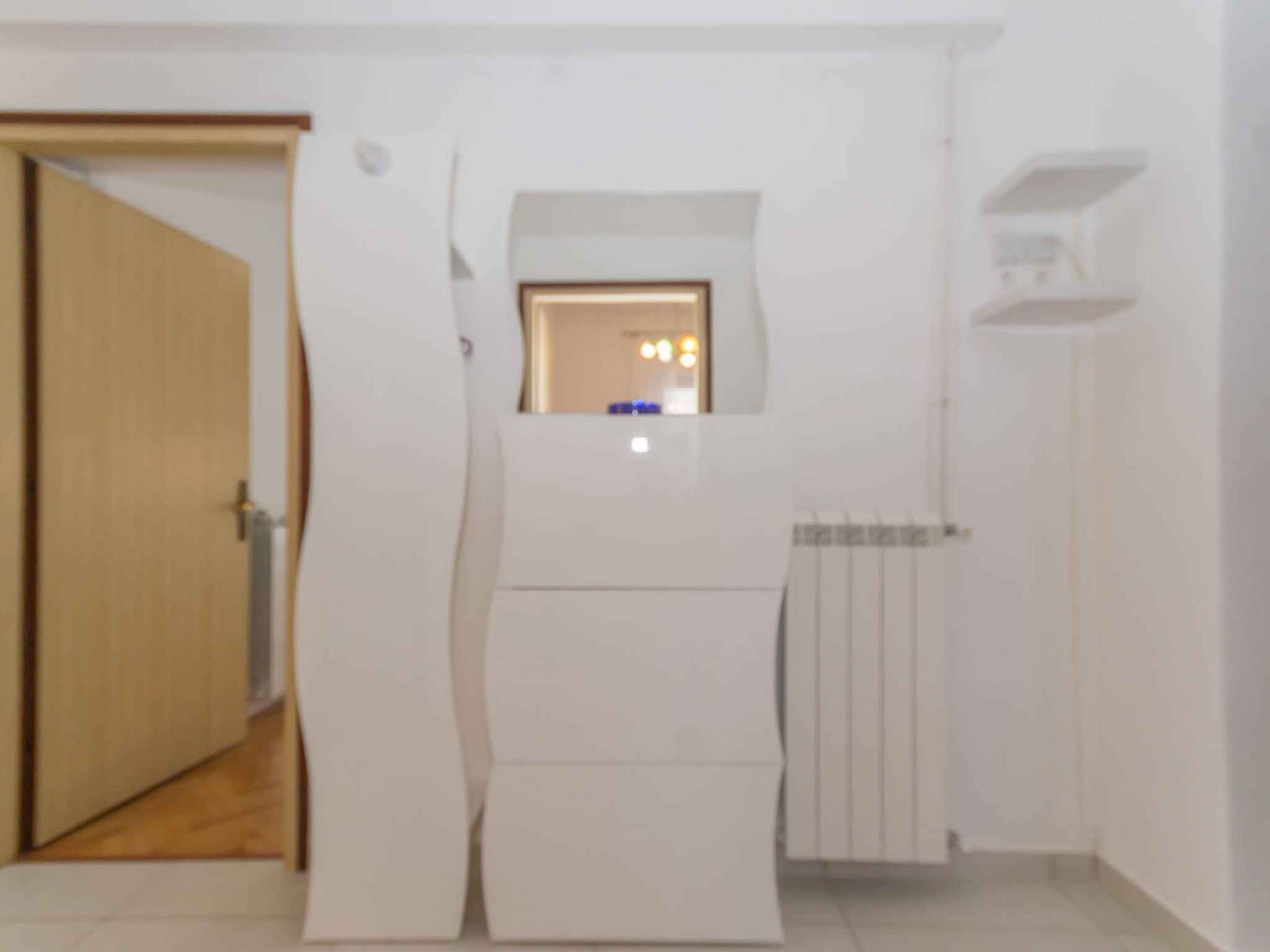 Quarto com porta, radiador e pequena janela com luzes.