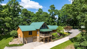 A two-story log cabin with a green metal roof, stone foundation, and a covered porch with outdoor seating. - ✶Appalachian Mt Cabin, Mt Views, 3BR 3BA, Fiber Wifi, Family, Hiking, Waterfalls (Unicoi)