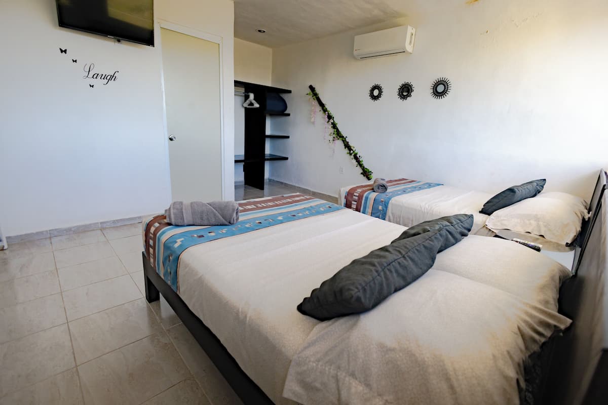 A bedroom with two beds, a wardrobe, and a TV.