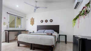 A bedroom with a bed, a desk, a chair, a ceiling fan, and an air conditioner. - Hotel Las Palmas Puerto Morelos (Puerto Morelos)