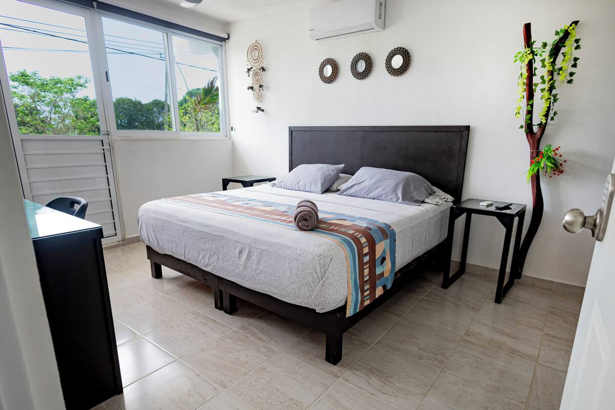 A bedroom with a bed, bedside tables, a desk, and a window.
