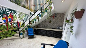 A hotel interior with a staircase, a blue chair, and a mural of parrots. - Hotel Las Palmas Puerto Morelos (Puerto Morelos)