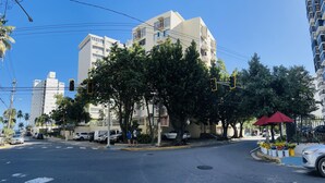 A street intersection with modern buildings, traffic lights, and a red umbrella. - Lovely beach studio - High speed internet! (San Juan)