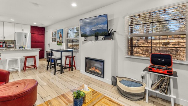 A modern living room with a fireplace, a television, and a cozy seating area. - Beaver Street Stone Lodge w/AC, Fully Fenced Yard, W/D, 3 Smart TVs, Speedy WiFi (Flagstaff)