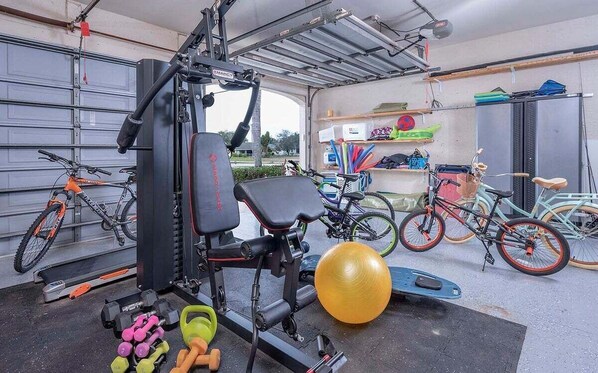 A home gym with exercise equipment, dumbbells, and bicycles.