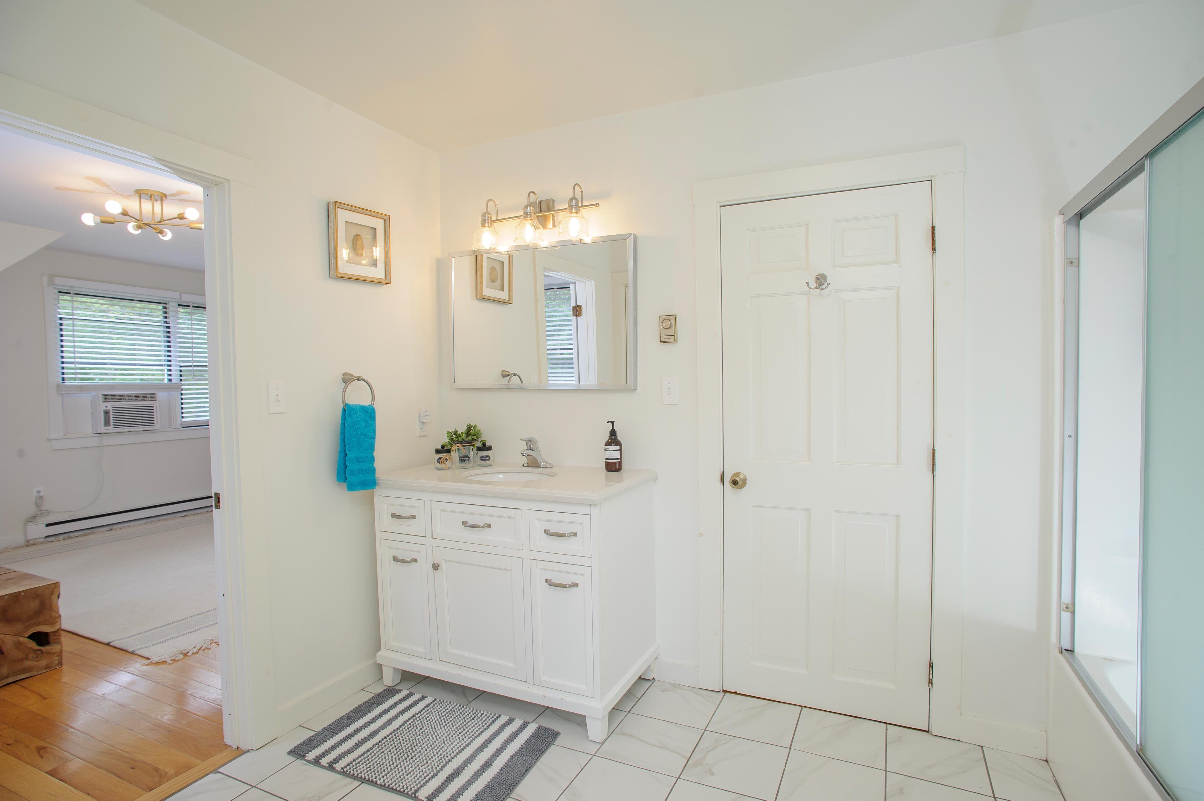 A bathroom with a white vanity, a large mirror, and a door.