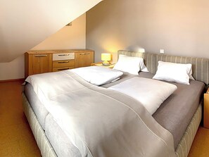 A bedroom with a bed, bedside table, lamp, and a wooden dresser.