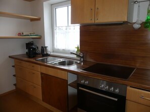 A kitchen with wooden cabinets, a stainless steel sink, a coffee maker, and an oven. - Anneliese by Interhome (Saalfelden am Steinernen Meer)