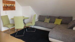 A modern living room with a grey sofa, green chairs, and a small round table. - Anneliese by Interhome (Saalfelden am Steinernen Meer)