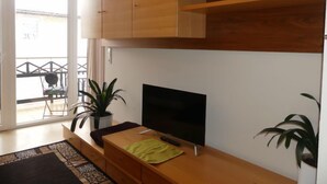 A modern living room with a flat-screen TV, wooden cabinets, and potted plants. - Anneliese by Interhome (Saalfelden am Steinernen Meer)