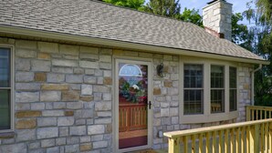 A stone house with a wooden deck and a mailbox.