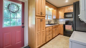 A kitchen with wooden cabinets, a stainless steel refrigerator, a microwave, and a stove.
