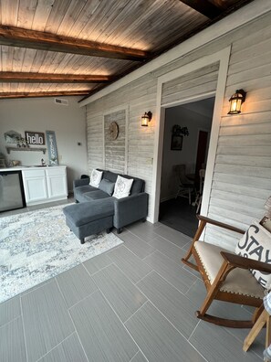 A cozy living room with a grey sectional sofa, a wooden rocking chair, a kitchen area, and a dining space. - Restored farmhouse just steps from the Katy Trail (Rhineland)