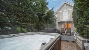 Un jacuzzi en un patio trasero con un porche y una casa al fondo.