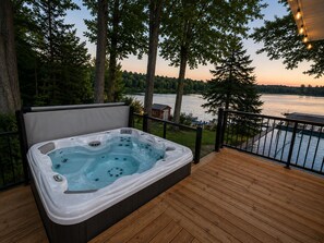 A hot tub on a wooden deck with a lake view.