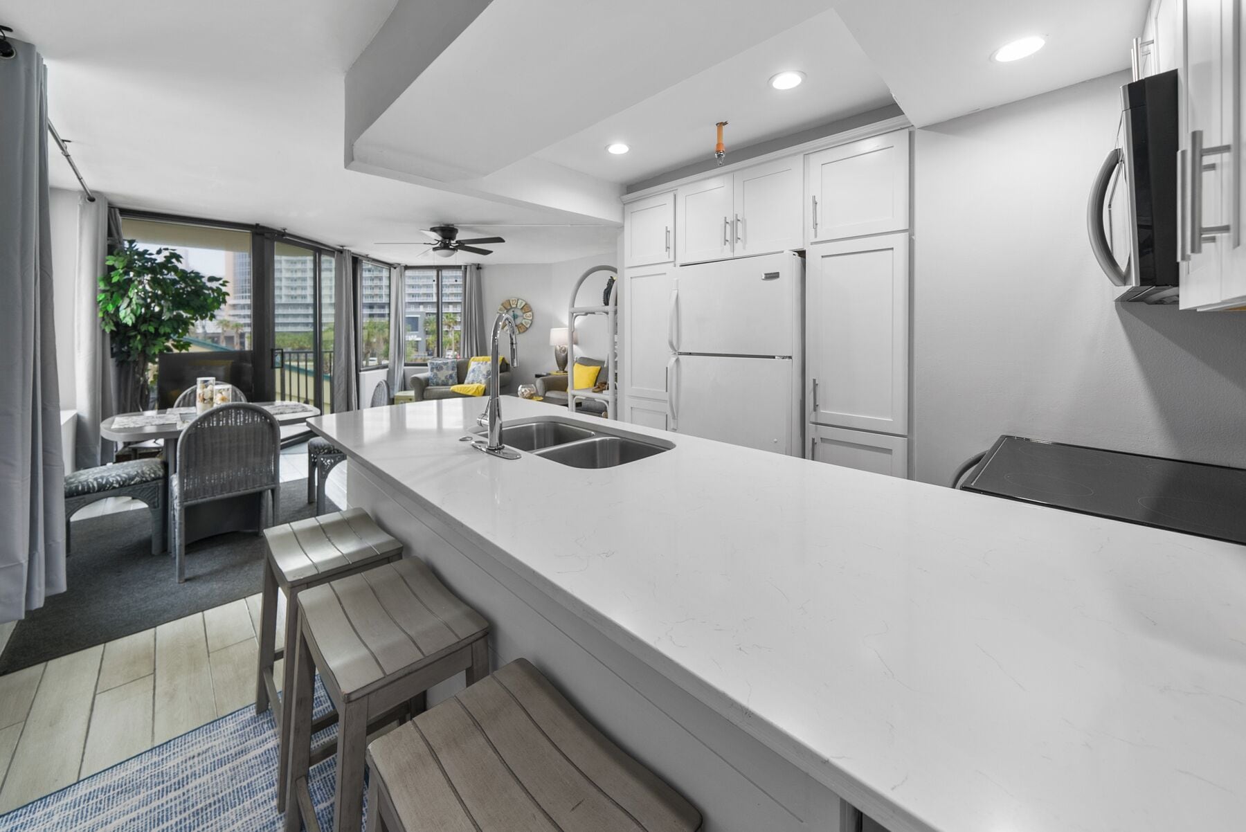 Una cocina moderna con armarios blancos, una isla grande y un comedor con sillas de mimbre.