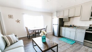 A modern kitchen with white cabinets, a stainless steel refrigerator, and a granite countertop. - Surfside 62 - Steps to the Ocean (Crescent City)