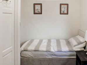 A single bed with striped bedding, a bedside table, and two framed pictures on the wall. - Goudhurst by Interhome (Staplehurst)