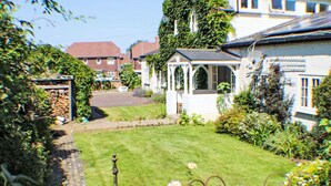 A well-maintained garden with a lawn, a metal bench, and a gazebo.
