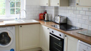 A compact kitchen with a washing machine, a toaster, and a stove.