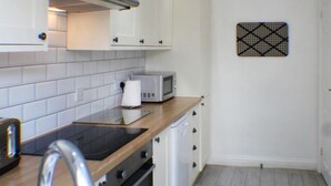 A small kitchen with white cabinets, a microwave, a toaster, and a wooden countertop.