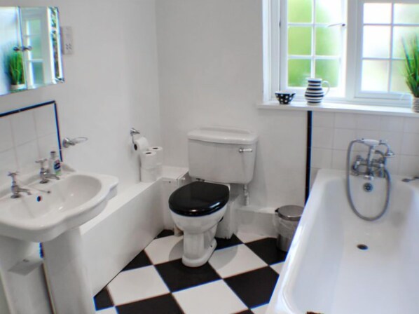 A bathroom with a black and white checkered floor, a white toilet, a white sink, and a bathtub.