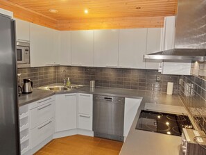A modern kitchen with white cabinets, a stainless steel sink, and a built-in dishwasher. - Vacation home Tiera by Interhome (Salla)