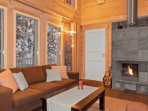 A cozy living room with a wooden interior, a fireplace, a sofa, and a table.