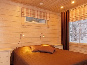 A cozy bedroom with a bed, bedside tables, a window with curtains, and a wall-mounted light fixture. - Vacation home Tiera by Interhome (Salla)