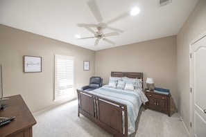 A bedroom with a bed, a chair, a desk, a nightstand, a ceiling fan, and two framed pictures on the wall. - Right At Home-Midland Retreat with covered patio (Midland)