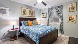 Ein Schlafzimmer mit einem Bett, Nachttischlampen, einer Uhr, einem Deckenventilator und Kunstwerken an den Wänden.