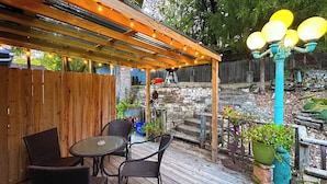 Eine Holzterrasse mit Sitzgelegenheiten im Freien, Lichterketten und Topfpflanzen.