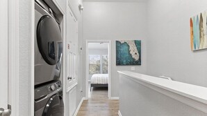 A laundry room with a washing machine and dryer, a hallway leading to a bedroom, and a wall with a map artwork. - Featured- 3 Bedroom 3 Bath Private Pool! Windsor Hills (Kissimmee)