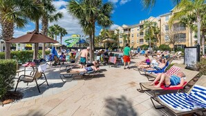 A poolside area with sun loungers, palm trees, and a water slide. - Featured- 3 Bedroom 3 Bath Private Pool! Windsor Hills (Kissimmee)