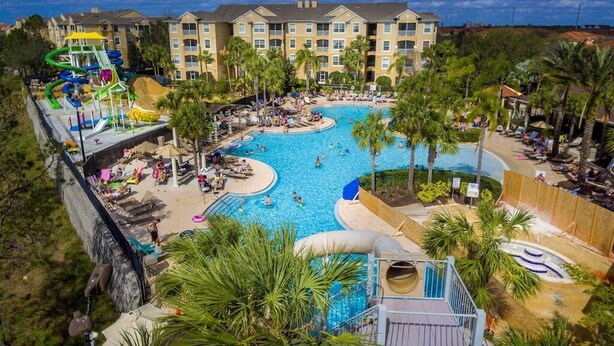 A resort with a large swimming pool, palm trees, and a water slide. - Featured- 3 Bedroom 3 Bath Private Pool! Windsor Hills (Kissimmee)