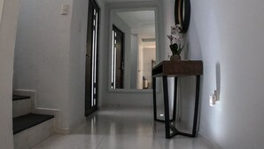A hallway with a tiled floor, a wooden table with a vase, and a mirror on the wall. - Beautiful house w heated private pool/ downtown (Tequisquiapan)