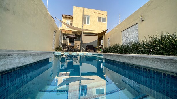 A swimming pool with tiled edges, surrounded by walls and a building with a flat roof and windows. - Beautiful house w heated private pool/ downtown (Tequisquiapan)