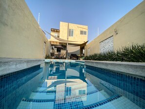 A swimming pool with tiled edges, surrounded by walls and a building with a flat roof and windows. - Beautiful house w heated private pool/ downtown (Tequisquiapan)