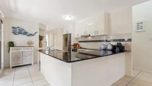 Una cocina moderna con una isla central, armarios blancos y un salpicadero de azulejos.