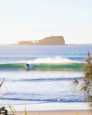 Un surfista montando una ola, con una isla al fondo.