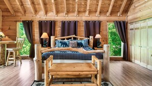 Une chambre dans une cabane en bois, comprenant un lit, deux tables de chevet, un bureau et une chaise.