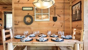 Une table de salle à manger en bois, mise avec des assiettes, des verres et un lustre.