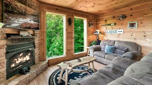 L’intérieur chaleureux d’un chalet avec une cheminée en pierre, un canapé et une enseigne indiquant « Lodge ».
