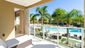 Ein Balkon mit Blick auf einen Pool, inklusive Tür, Sofa und Geländer.