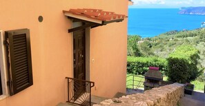 Un edificio con un muro in pietra, una porta in legno e una finestra con persiane.