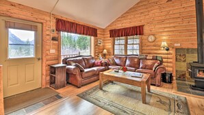 Interior acollidor d'una cabana amb parets de fusta, una llar de foc, sofàs de cuir i una taula de centre de fusta.