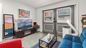 Ein modernes Wohnzimmer mit einer Couch, einem Couchtisch, einem Kamin und einem großen Fenster mit Jalousien.