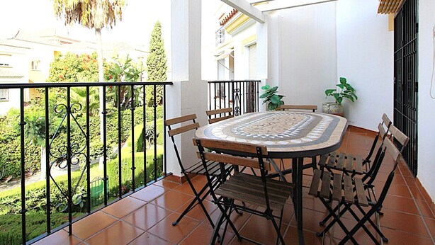 A balcony with a tiled floor, a round table with chairs, and a potted plant. - Valparaiso Apartment Burriana Beach (Nerja)